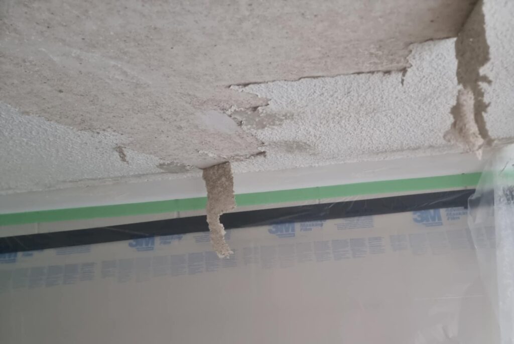 Asbestos texture pealed off half way to show exposed ceiling substrate. 