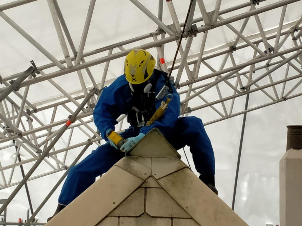 Certified technician safely removing asbestos roofing sheets