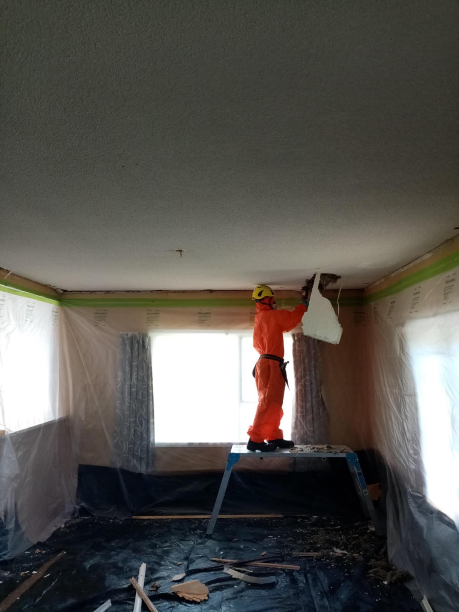 Hazard Pro asbestos removal team in full PPE during ceiling remediation.